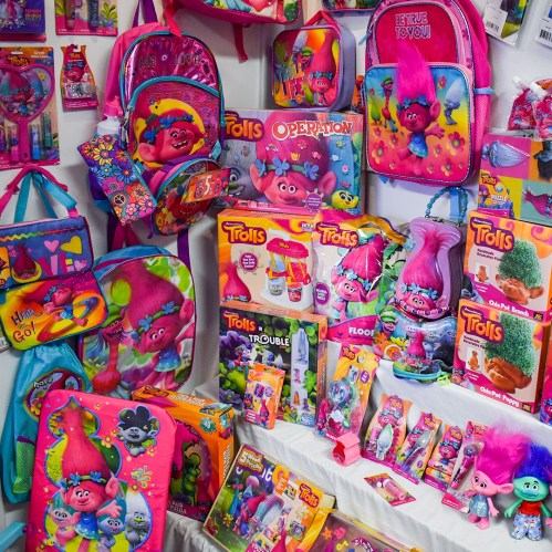 A colorful display of Trolls-themed backpacks, toys, and accessories featuring vibrant characters and designs.