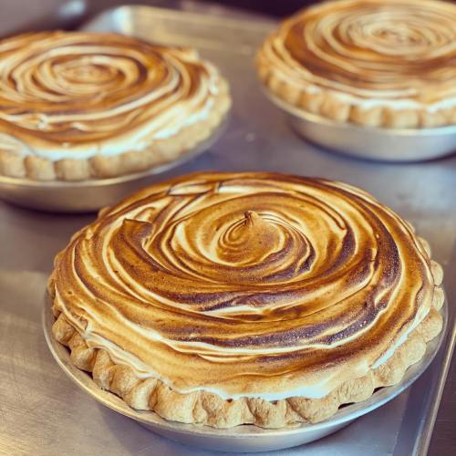 Three beautifully baked pies with golden-brown meringue swirls on top, resting on a silver tray.