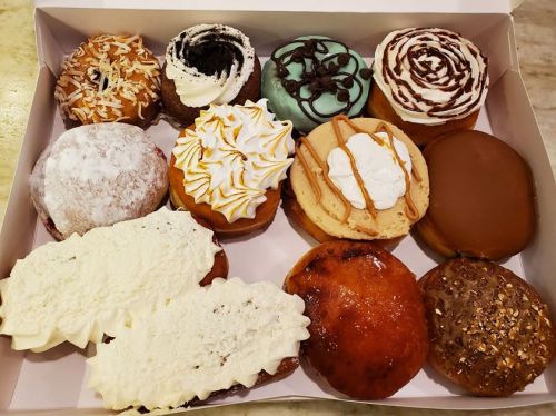 A box filled with a variety of colorful and decorated donuts, featuring different toppings and fillings.