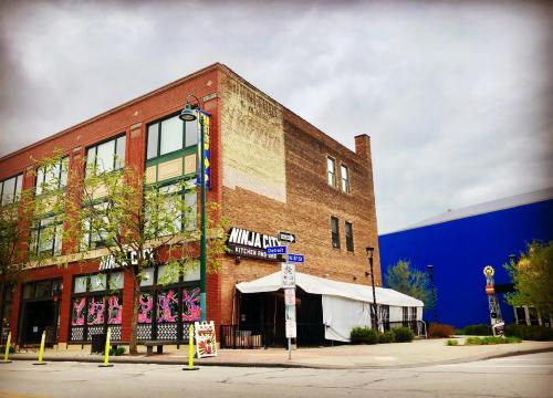 A brick building with "Ninja City" signage, colorful artwork, and a blue wall in the background under a cloudy sky.
