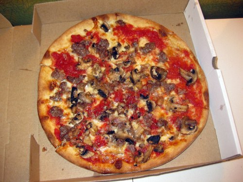 A pizza topped with sausage, mushrooms, and tomato sauce, in a cardboard box.
