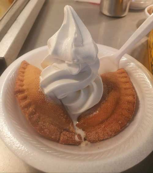 A dessert featuring soft-serve ice cream on top of two golden-brown pastry shells on a white plate.