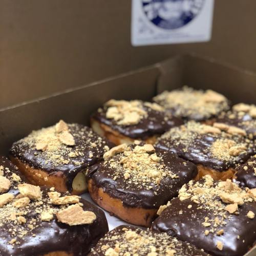 A box of chocolate-covered donuts topped with crushed graham crackers.