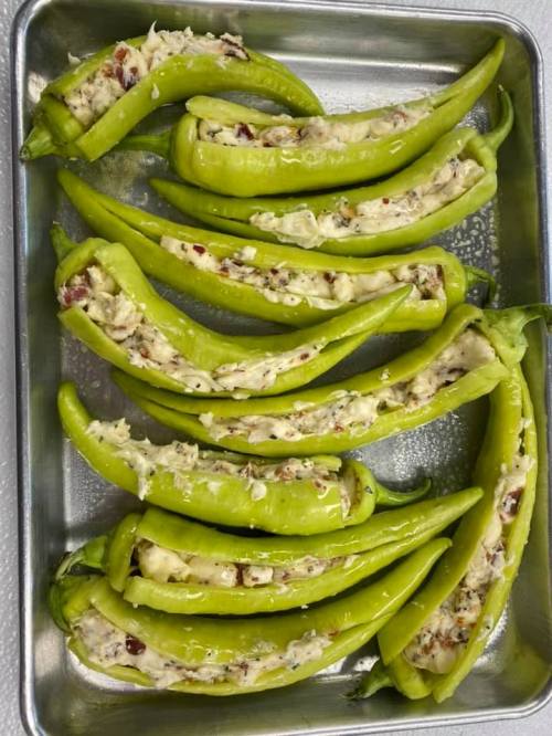 A tray of green peppers stuffed with a creamy filling, arranged neatly in a single layer.