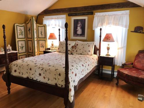 Cozy bedroom with a four-poster bed, floral bedding, yellow walls, and vintage decor, including lamps and a wardrobe.
