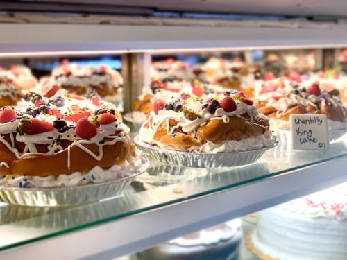 Colorful king cakes topped with frosting, berries, and sprinkles displayed in a bakery case.