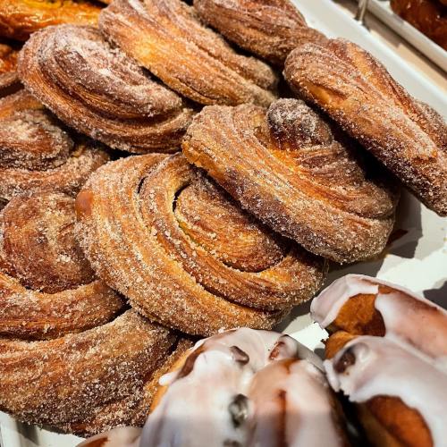 A close-up of freshly baked, sugary pastries with a golden-brown swirl and a dusting of sugar on top.