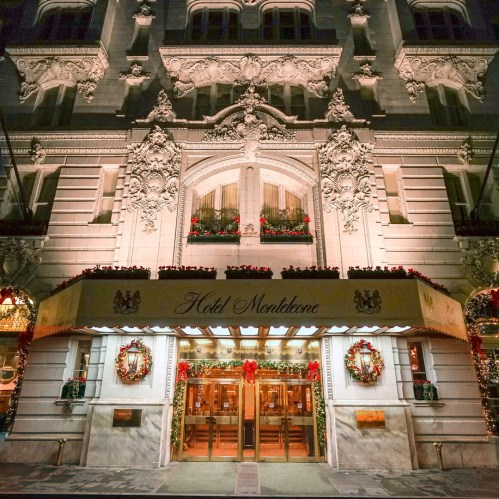 Elegant hotel entrance adorned with festive wreaths and holiday decorations, illuminated at night.