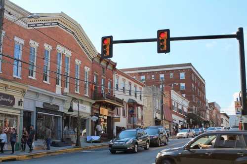 A busy street scene with shops, cars, and a traffic light showing red in a small town.