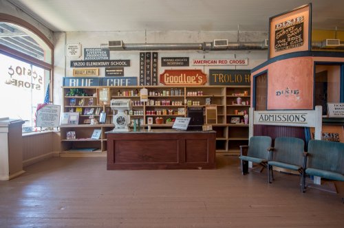 Interior of a vintage store with wooden floors, shelves of goods, and signs for local businesses and organizations.