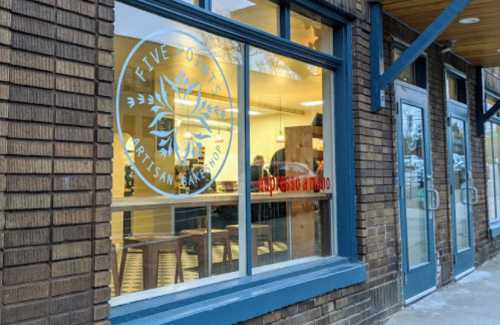 Exterior view of a bakery with large windows displaying the logo and interior seating.