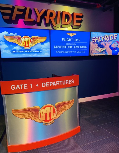 A colorful airport-style check-in area for BTL Airlines, featuring screens displaying flight information and boarding details.