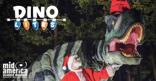 A dinosaur wearing a Santa hat stands next to a person in a Santa suit, surrounded by trees at night.