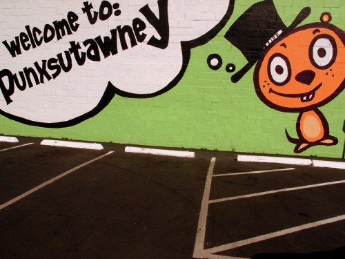 Colorful mural featuring a cartoon groundhog in a top hat with the text "Welcome to Punxsutawney" on a green wall.