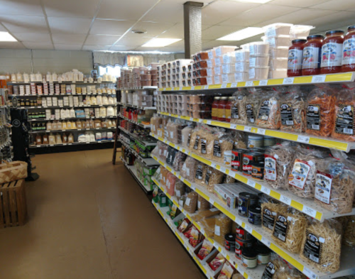 A well-stocked grocery aisle featuring various packaged foods, pasta, sauces, and dry goods on shelves.