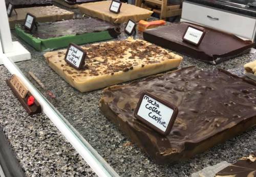 A display of various fudge flavors, including mocha coffee cookie, on a granite countertop with labels.