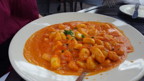 A plate of gnocchi in a creamy tomato sauce, garnished with herbs, served on a white dish.