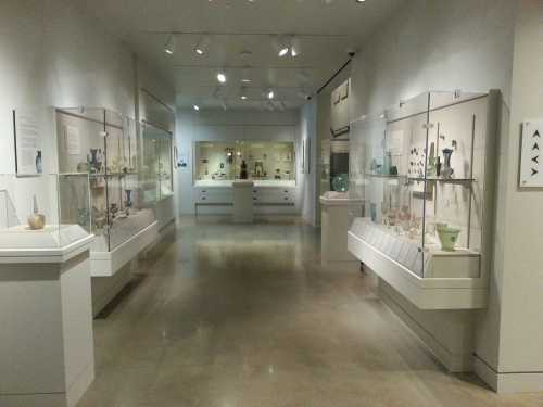 A spacious museum gallery featuring glass display cases with various artifacts and a polished concrete floor.