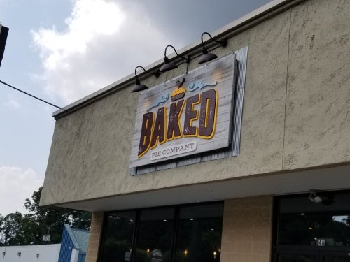 Sign for "Baked Pie Company" on a building exterior, featuring a rustic design and bright lettering.