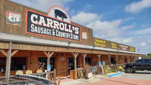 Exterior of Carroll's Sausage & Country Store, featuring wooden architecture and signage for various products.