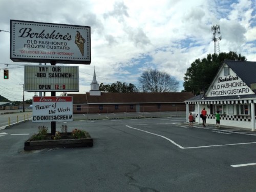 Sign for Berkshire's Old Fashioned Frozen Custard with a BBQ sandwich special, featuring a parking lot and nearby church.