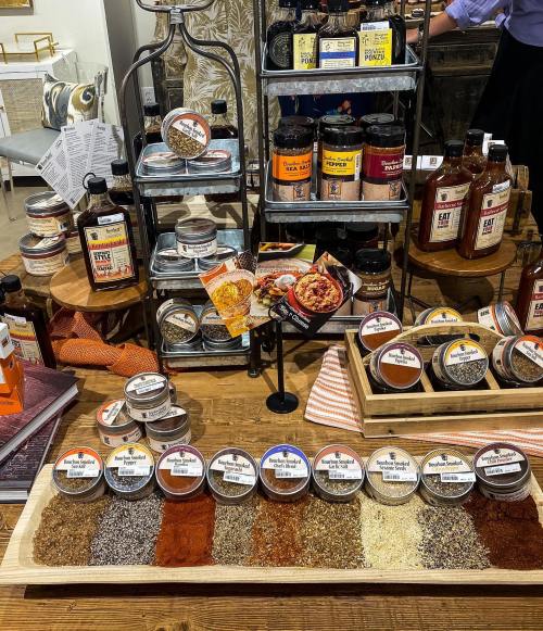A wooden display featuring various spice jars and containers arranged neatly on a table, with a backdrop of shelves.