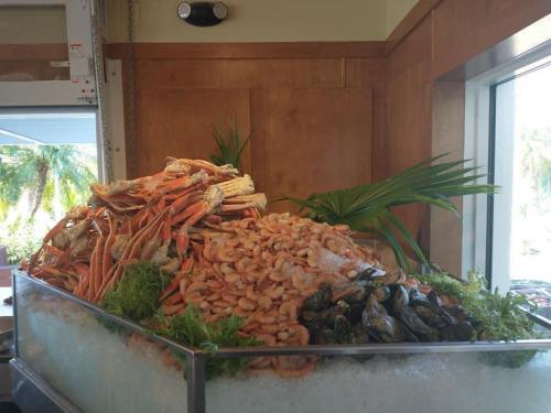 A large seafood display featuring a variety of shrimp, crab, and oysters on a bed of ice with decorative greenery.