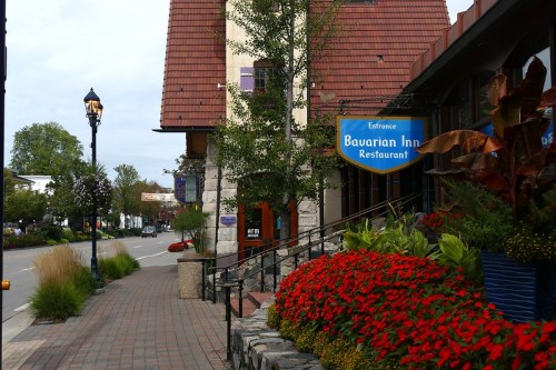 A charming street view featuring the Bavarian Inn Restaurant, lined with colorful flowers and greenery.