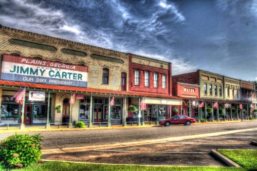 Historic storefronts in Plains, Georgia, featuring a sign for Jimmy Carter, with American flags lining the street.
