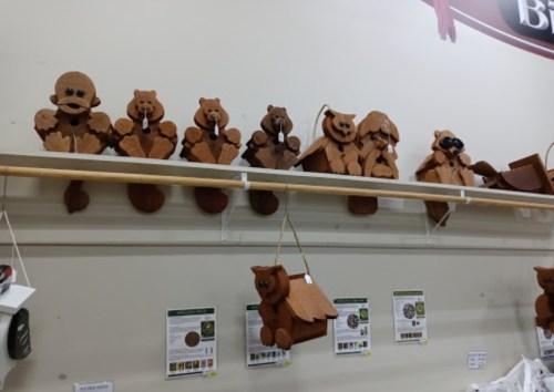 Wooden bear decorations in various shapes and sizes displayed on a shelf, with informational signs below.