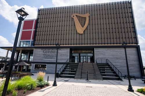 Exterior of the Guinness Open Gate Brewery, featuring a large harp logo and steps leading to the entrance.