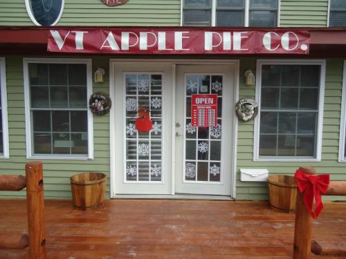 Exterior of VT Apple Pie Co. with double doors, festive decorations, and an "OPEN" sign.