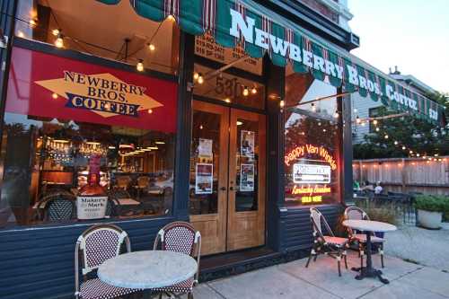 Exterior of Newberry Bros. Coffee, featuring outdoor seating and colorful signage, with warm lights in the evening.