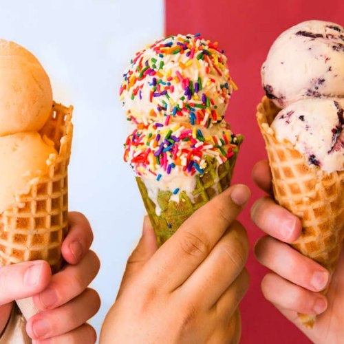 Three hands hold ice cream cones: one with a single scoop, one with two colorful scoops, and another with a scoop of chocolate.