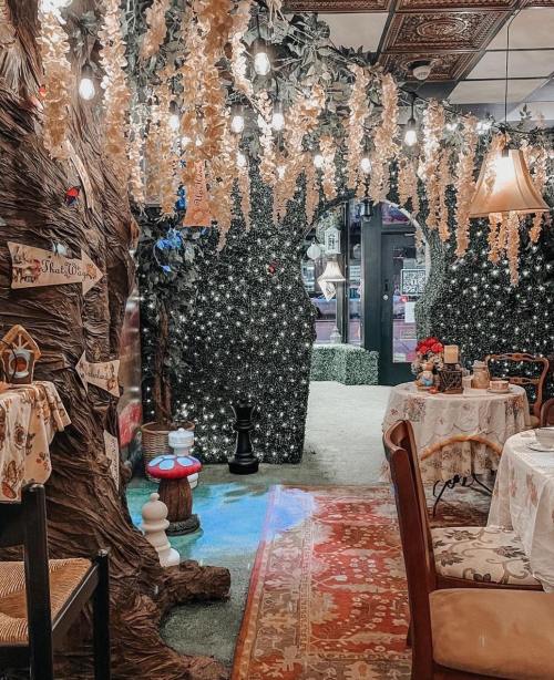 A whimsical restaurant interior with tree-like decor, fairy lights, and cozy tables set for dining.