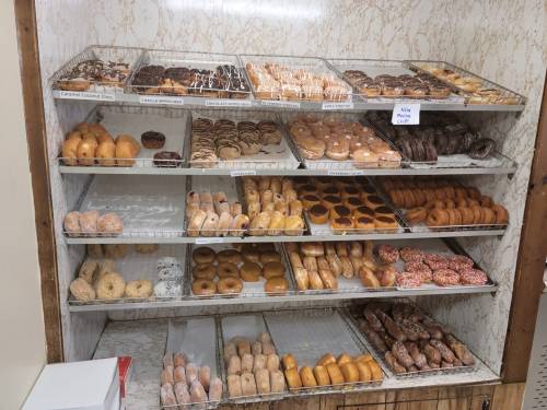 A display case filled with various types of donuts, including glazed, chocolate, and sprinkled varieties.