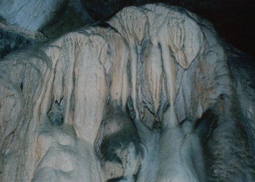 Close-up of textured cave formations with stalactites and stalagmites, showcasing natural mineral deposits.