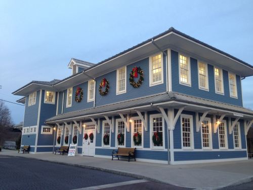 A blue building decorated with wreaths for the holidays, featuring large windows and a welcoming entrance.