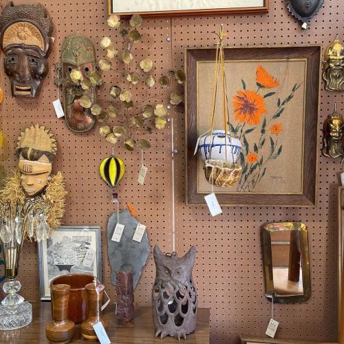 A collection of vintage items, including masks, artwork, and decorative objects, displayed on a pegboard wall.