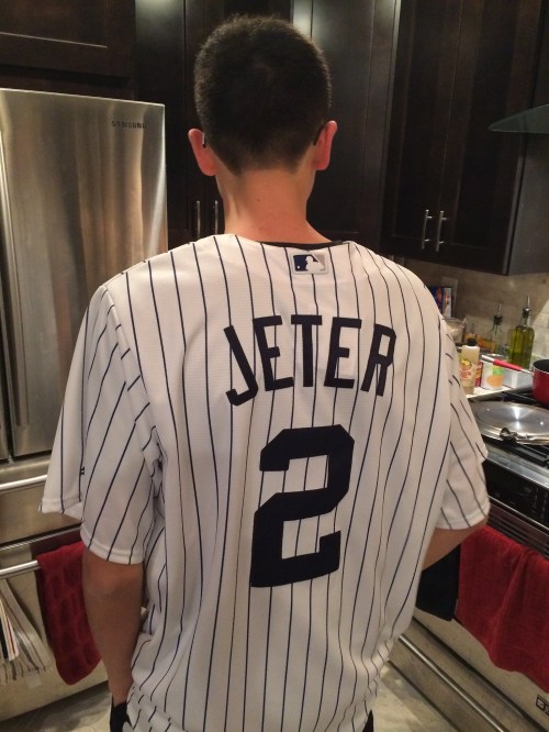 A person wearing a white pinstriped baseball jersey with "JETER" and the number "2" on the back, standing in a kitchen.