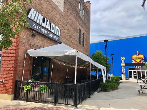 Exterior of Ninja City Kitchen and Bar with a tented patio and colorful building in the background.