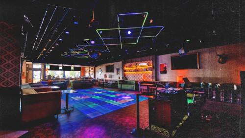 A vibrant lounge with colorful lighting, a dance floor, and cozy seating areas, creating a lively atmosphere.