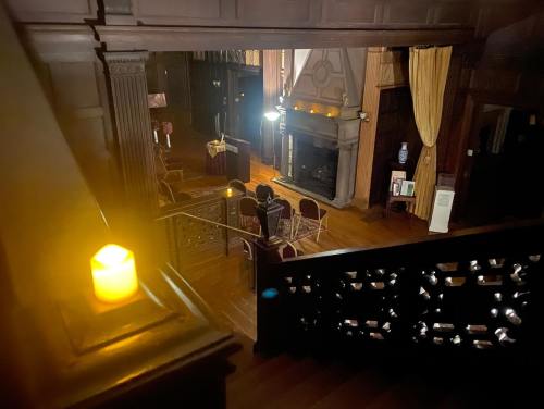 A dimly lit room with a fireplace, chairs arranged, and a candle on the staircase, creating a cozy atmosphere.