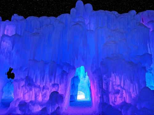 A stunning ice cave illuminated with blue and purple lights, creating a magical, otherworldly atmosphere.