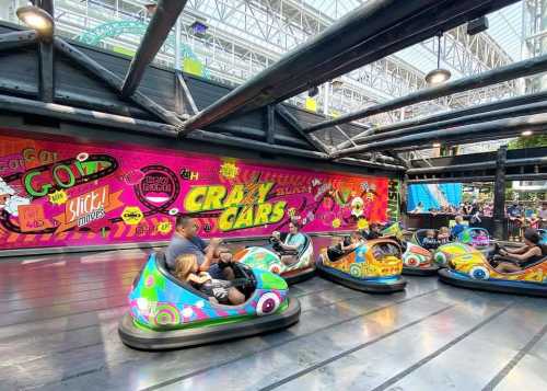 Colorful bumper cars on a vibrant amusement park ride, with a lively crowd and a bright, graffiti-style backdrop.