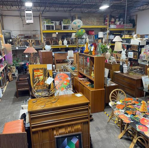 A spacious thrift store filled with various furniture, lamps, and decorative items on display.