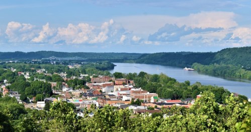 A scenic view of a river winding through a lush green landscape, with a small town visible along the banks.