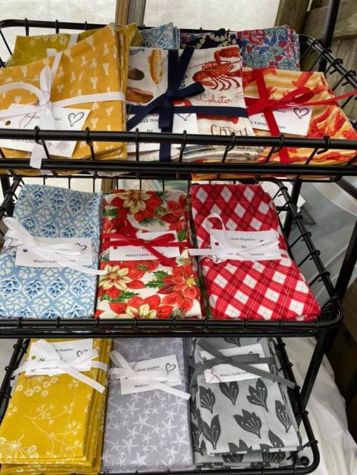 A display of colorful fabric napkins arranged on a rack, featuring various patterns and tied with ribbons.