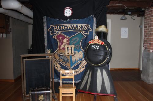 A Hogwarts-themed display featuring a train, a chair, and a large banner with the Hogwarts crest.