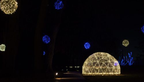 A lit dome structure surrounded by colorful glowing orbs in a dark outdoor setting.